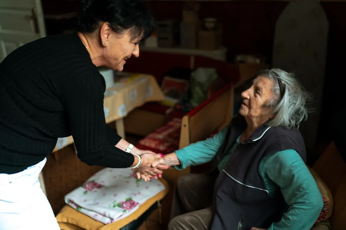 A carer warmly greeting an older woman at home